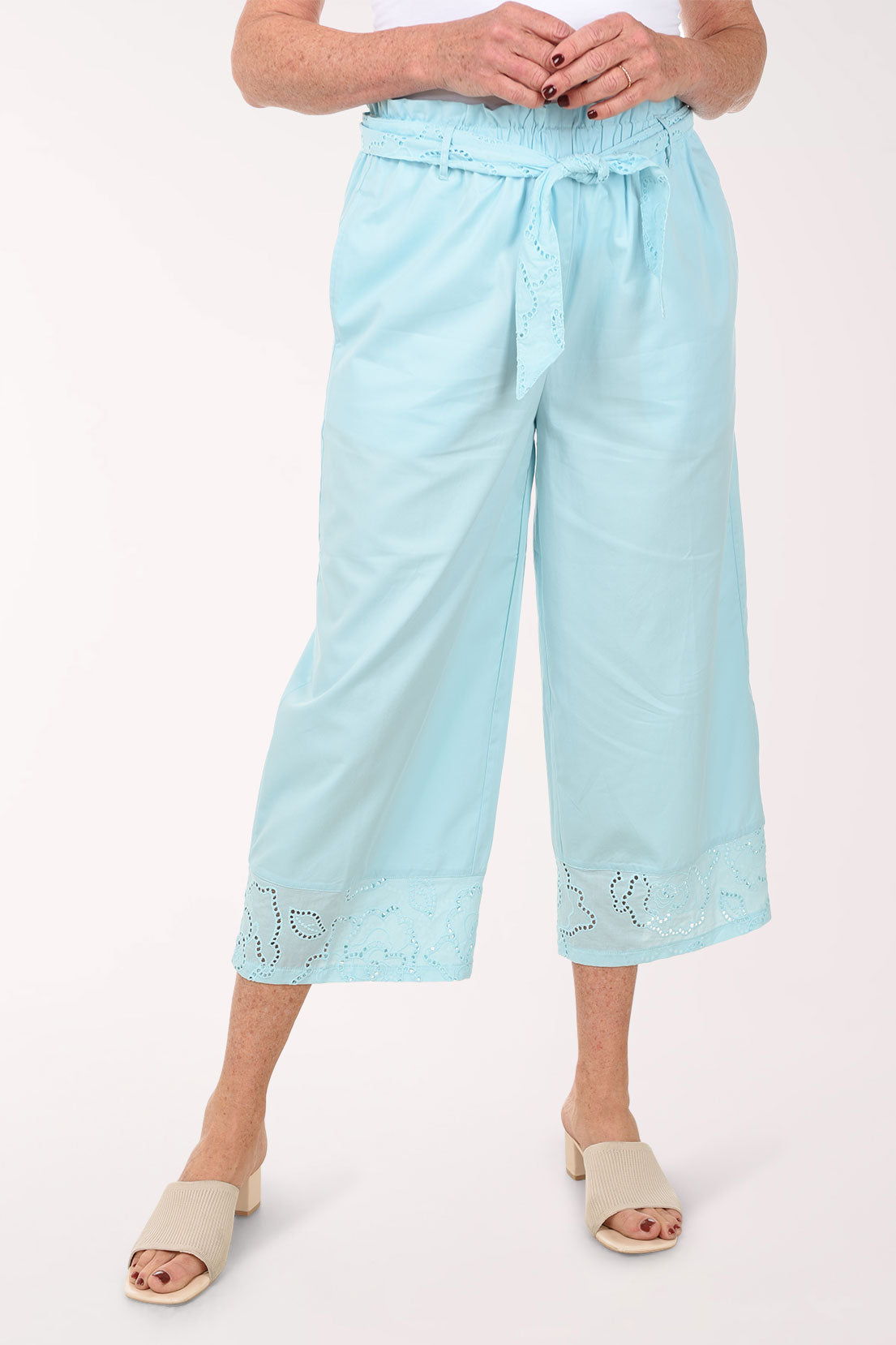 Light blue pants with lace details worn by a person on a white background