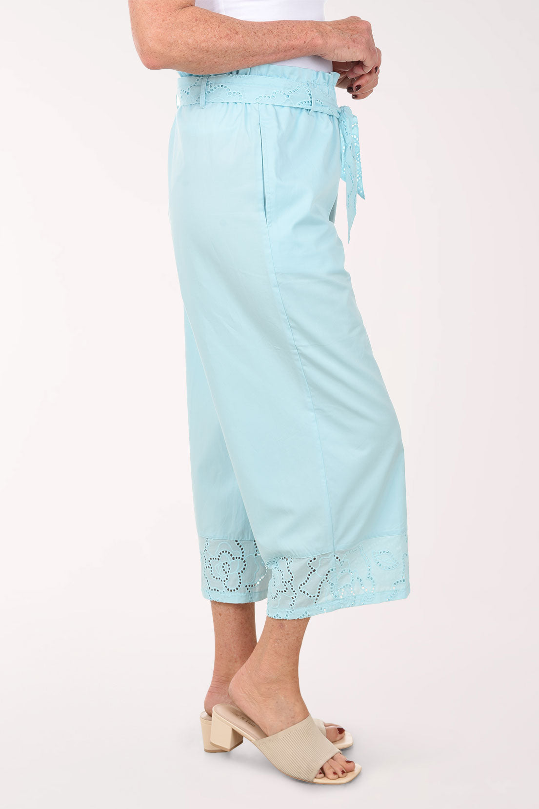 Light blue pants with lace details worn by a person on a white background