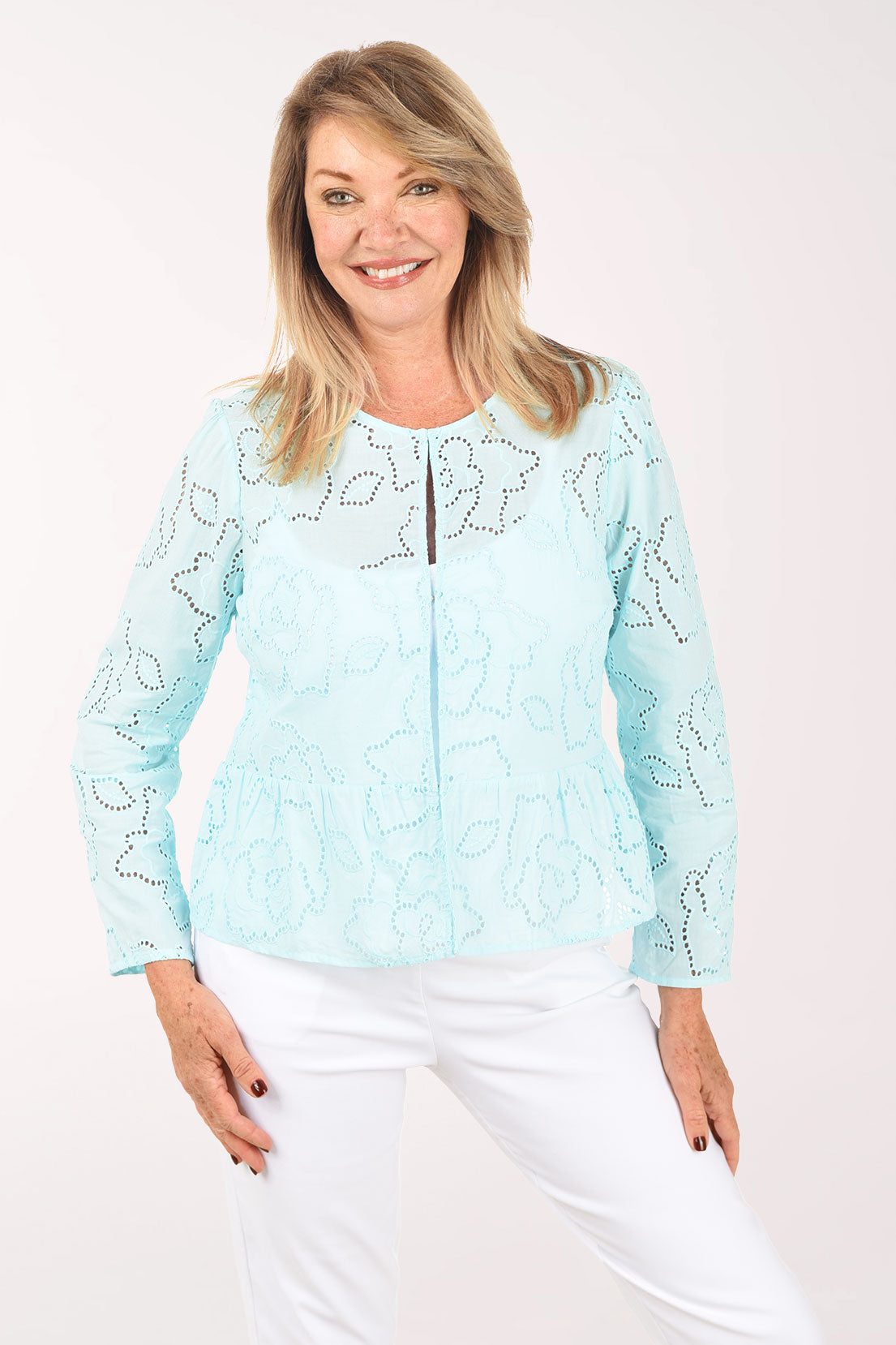 Woman wearing a light blue lace top and white pants on a white background