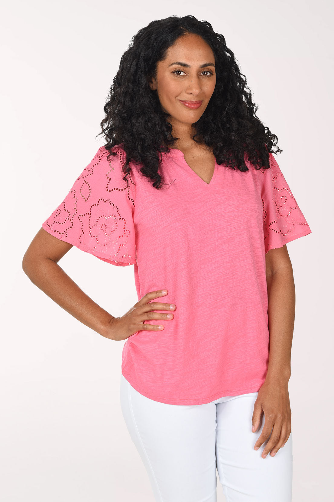 Woman wearing a pink blouse with floral lace sleeves on a white background