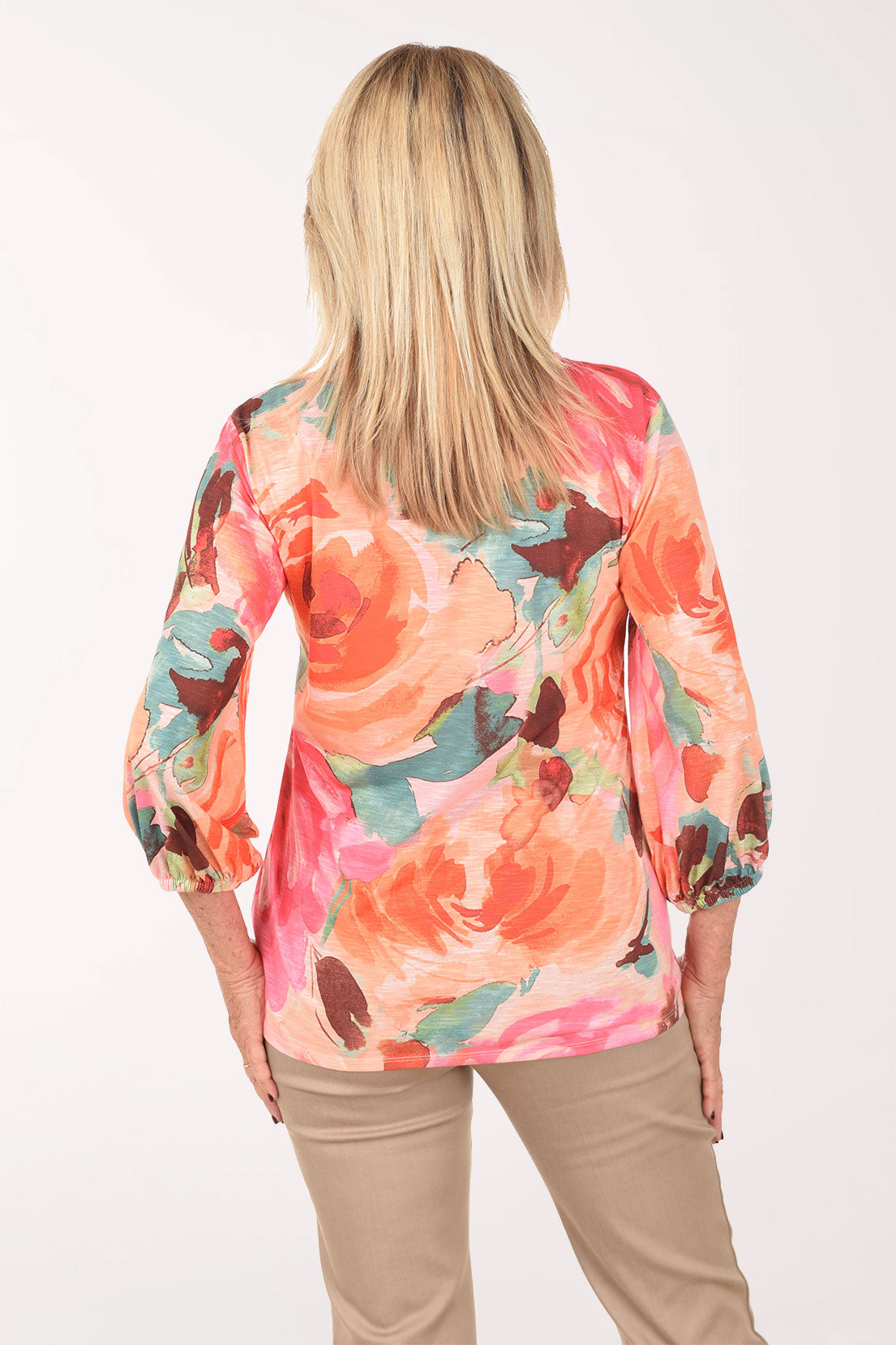 Woman wearing a colorful floral blouse against a white background