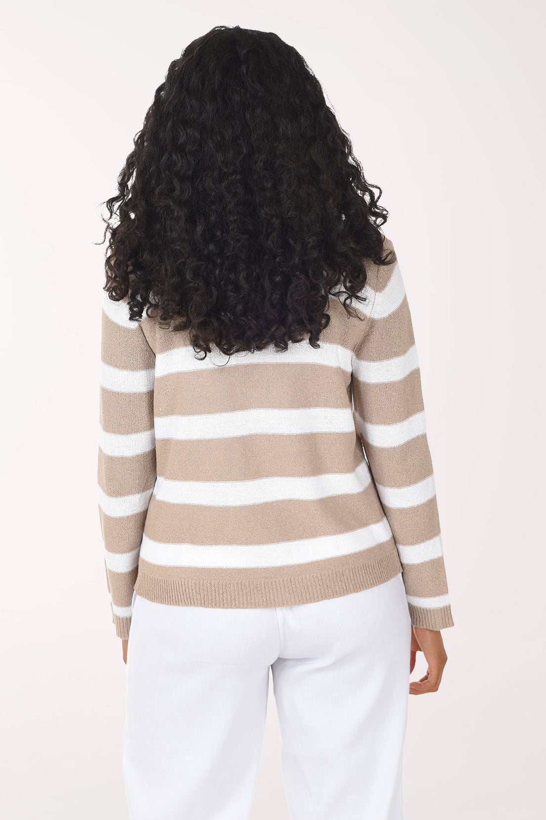 Woman wearing a beige and white striped sweater on a plain background