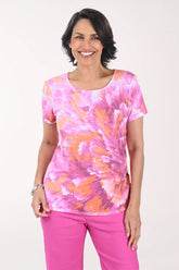 Woman wearing a pink and orange tie-dye shirt with pink pants on a white background