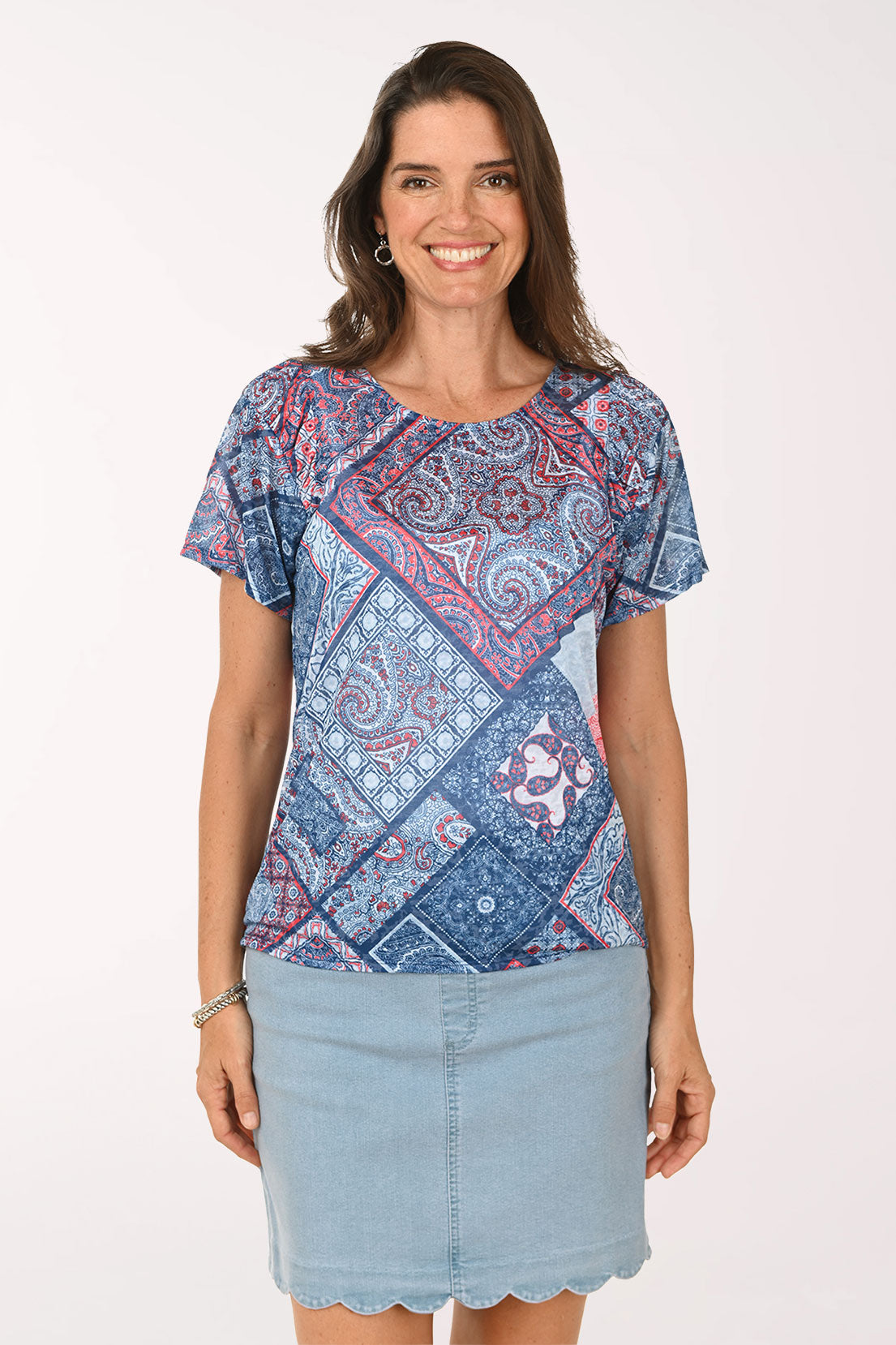 Woman wearing a patterned blue shirt and light blue skirt on a white background