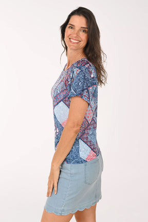 Woman wearing a patterned blue shirt and light blue skirt on a white background