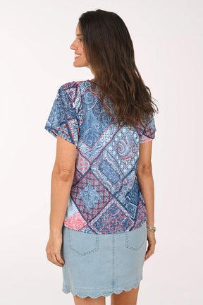 Woman wearing a patterned blue shirt and light blue skirt on a white background