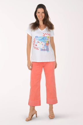 Woman wearing a white t-shirt with colorful design and coral pants on a white background