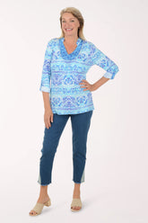 Woman wearing a blue patterned top and blue pants on a white background