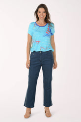 Woman wearing a blue t-shirt with sailboat design and dark blue jeans on a white background