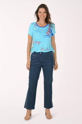 Woman wearing a blue t-shirt with sailboat design and dark blue jeans on a white background
