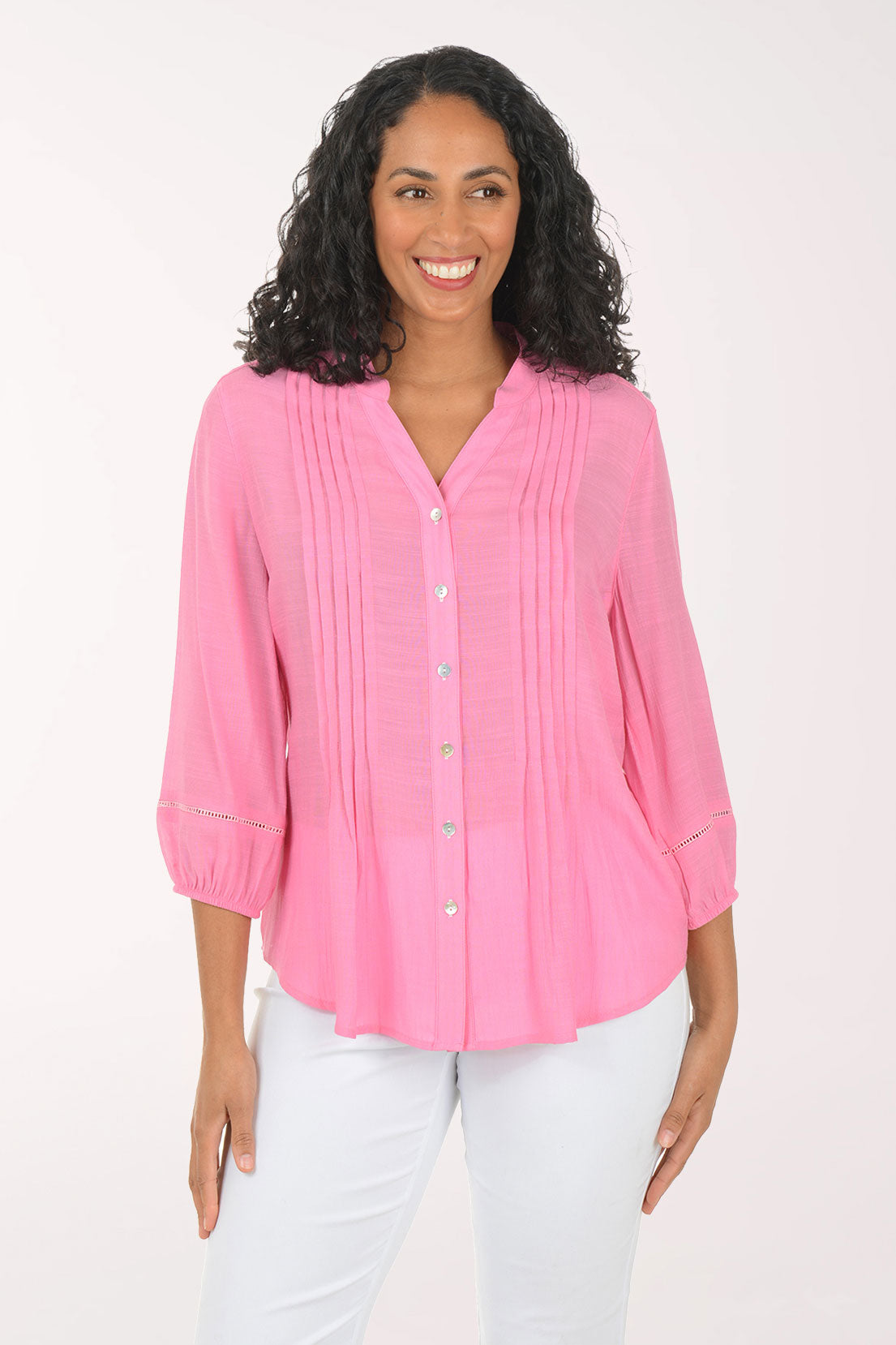 Woman wearing a pink blouse and white pants on a white background