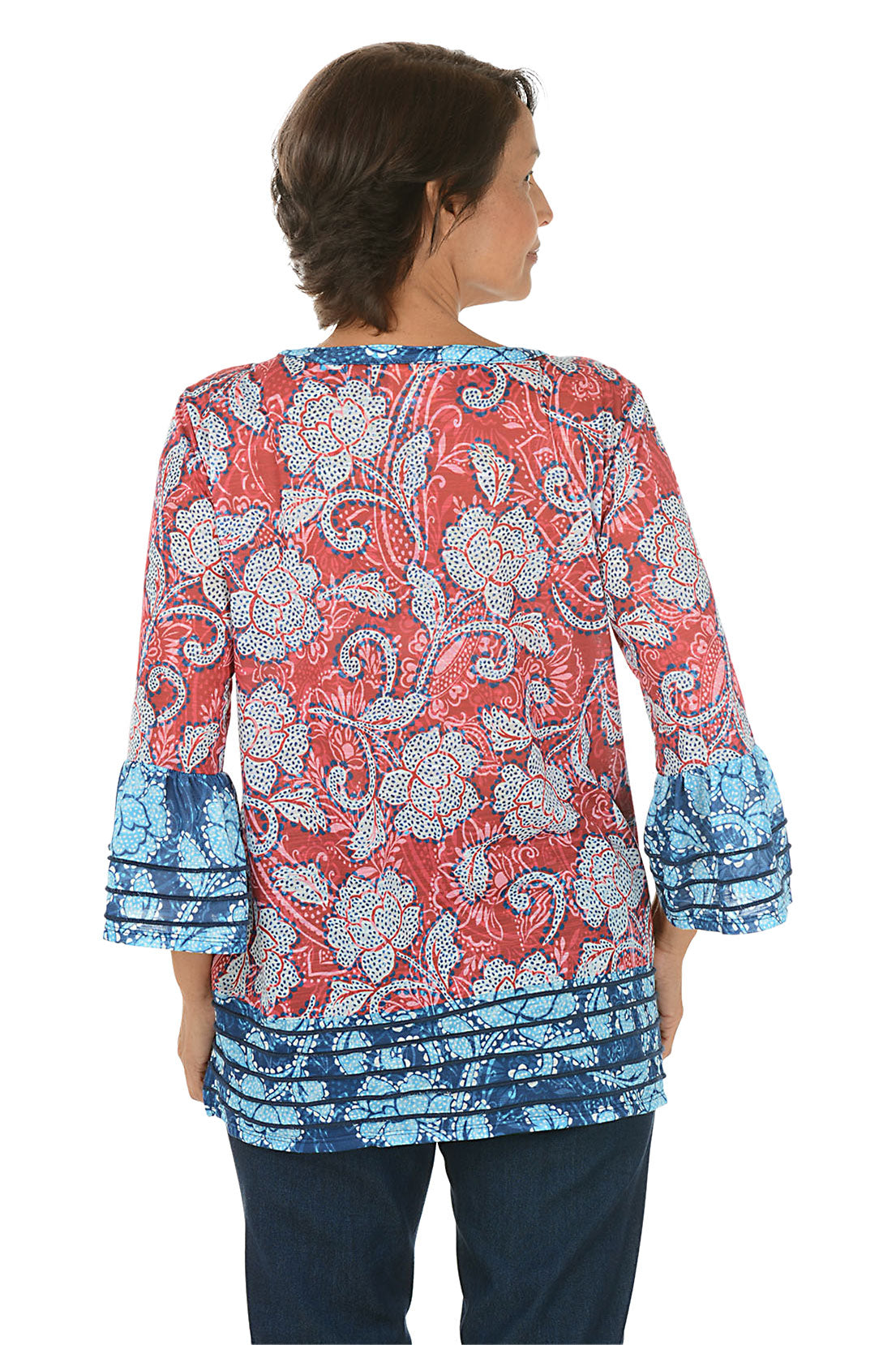 Woman wearing a patterned blouse with red and blue design on a white background. Back shot.