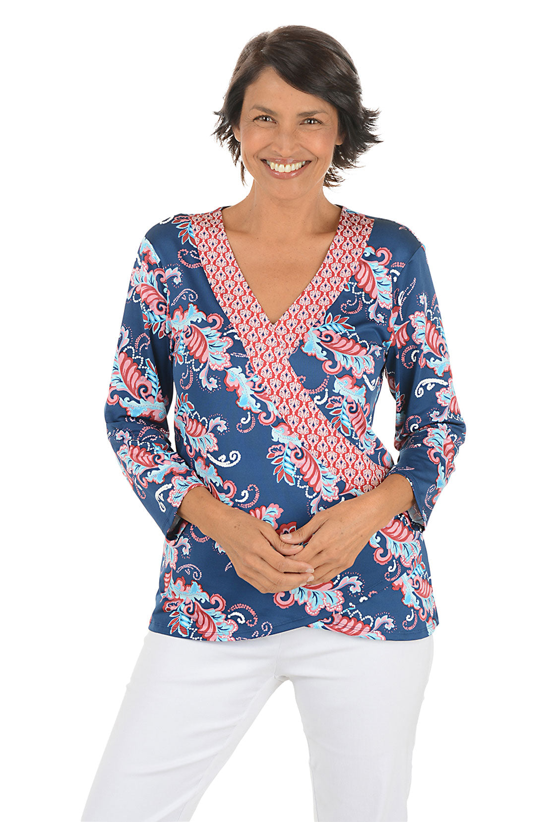 Woman wearing a colorful patterned blouse with a white background.