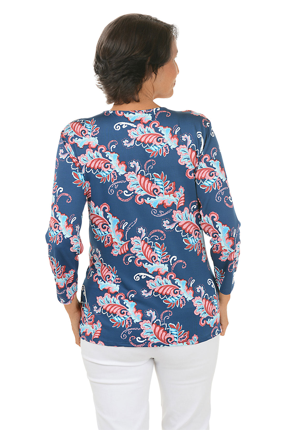 Woman wearing a colorful patterned blouse with a white background. Back shot.