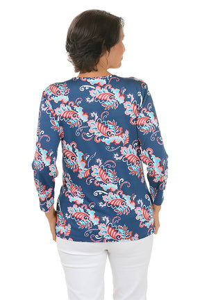 Woman wearing a colorful patterned blouse with a white background. Back shot.