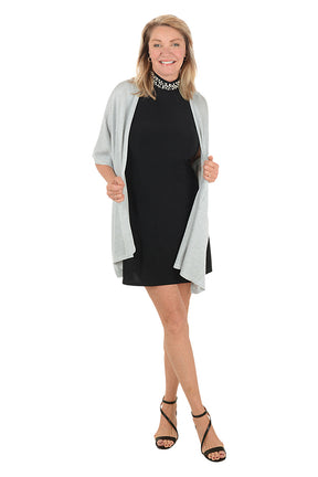 Woman wearing a black dress with a light gray cardigan on a white background