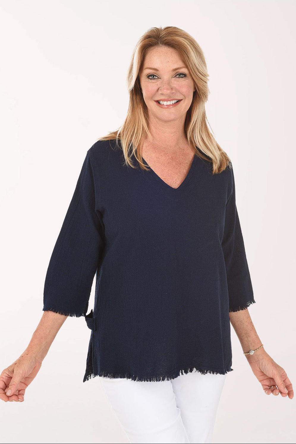 Woman wearing a navy blue blouse with white pants on a white background