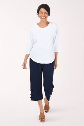 Woman wearing a white top and navy blue pants on a white background