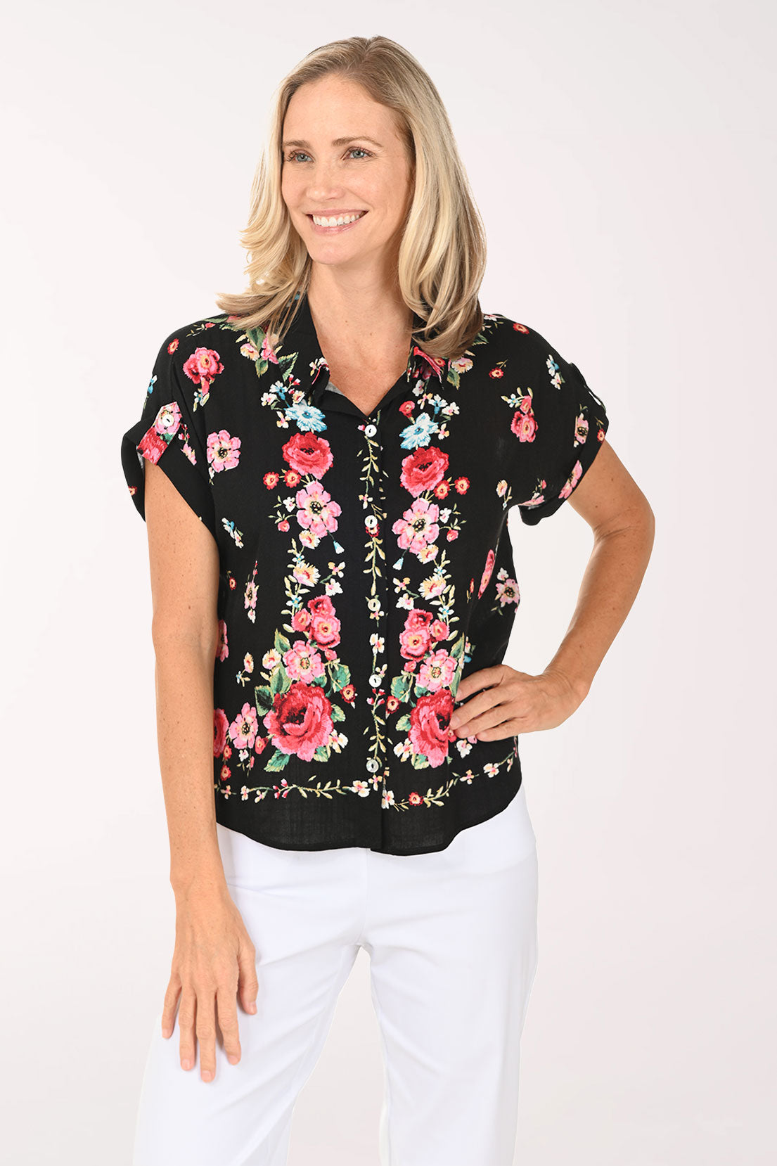 Woman wearing a black floral blouse with pink roses on a white background