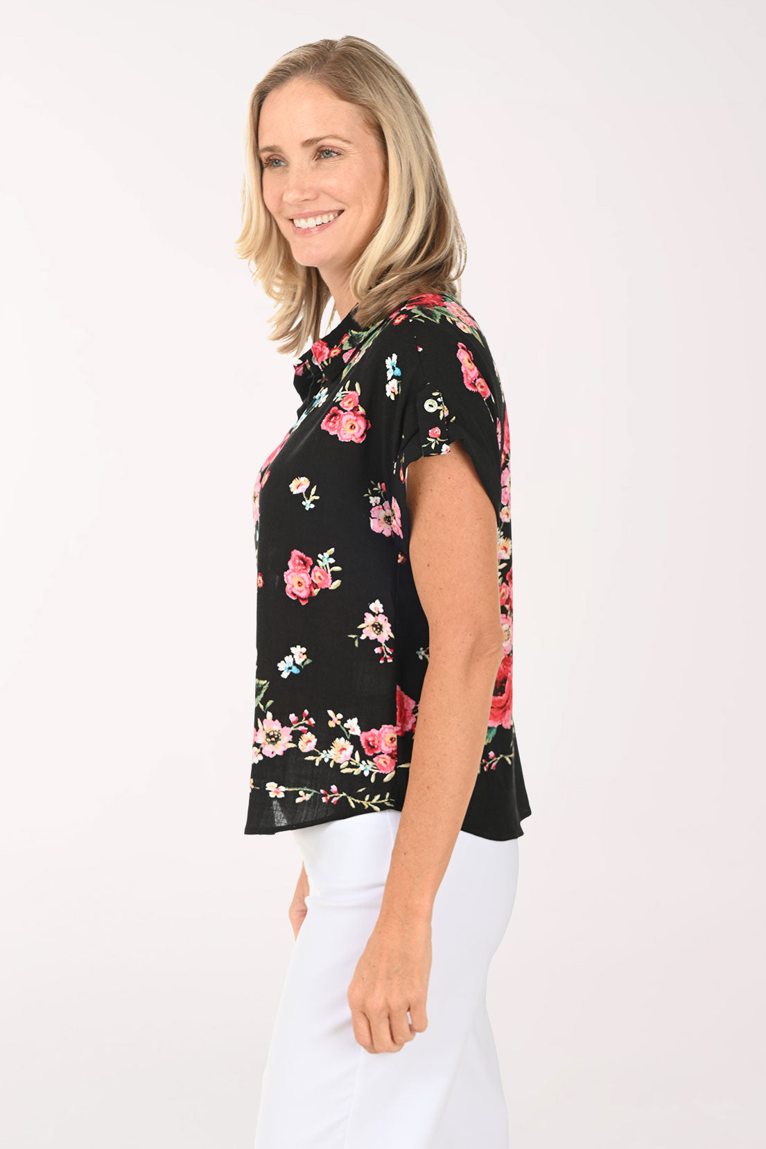 Woman wearing a black floral blouse with pink roses on a white background