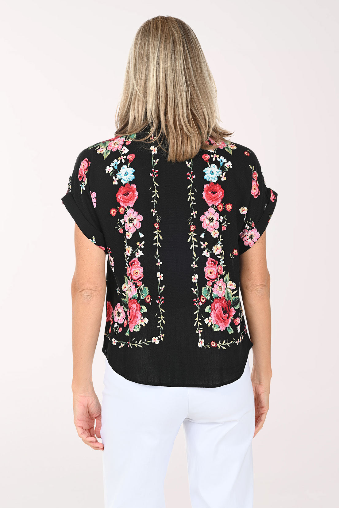 Woman wearing a black floral blouse with pink roses on a white background