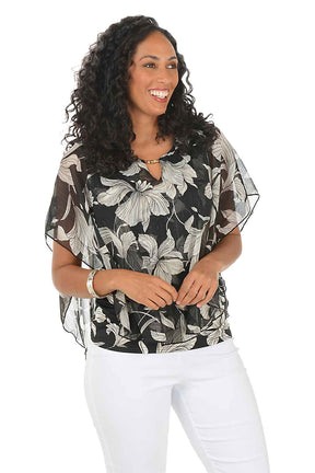 Woman wearing a floral blouse and white pants on a white background.