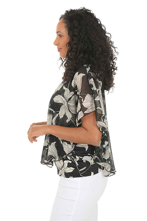 Woman wearing a floral blouse and white pants on a white background. Side shot.