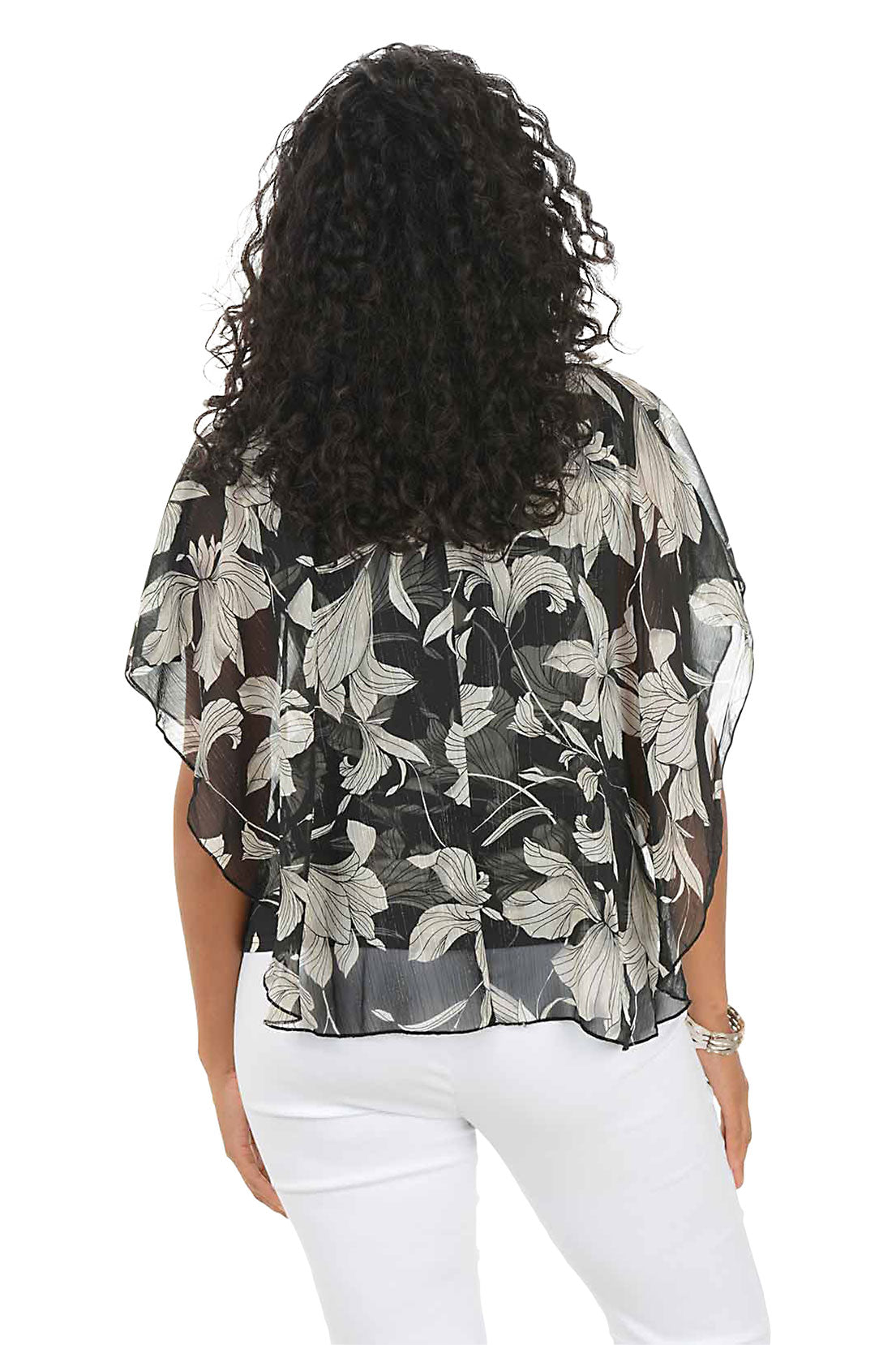 Woman wearing a floral blouse and white pants on a white background. Back shot.