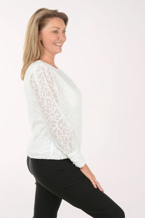 Woman wearing a white lace top and black pants on a white background