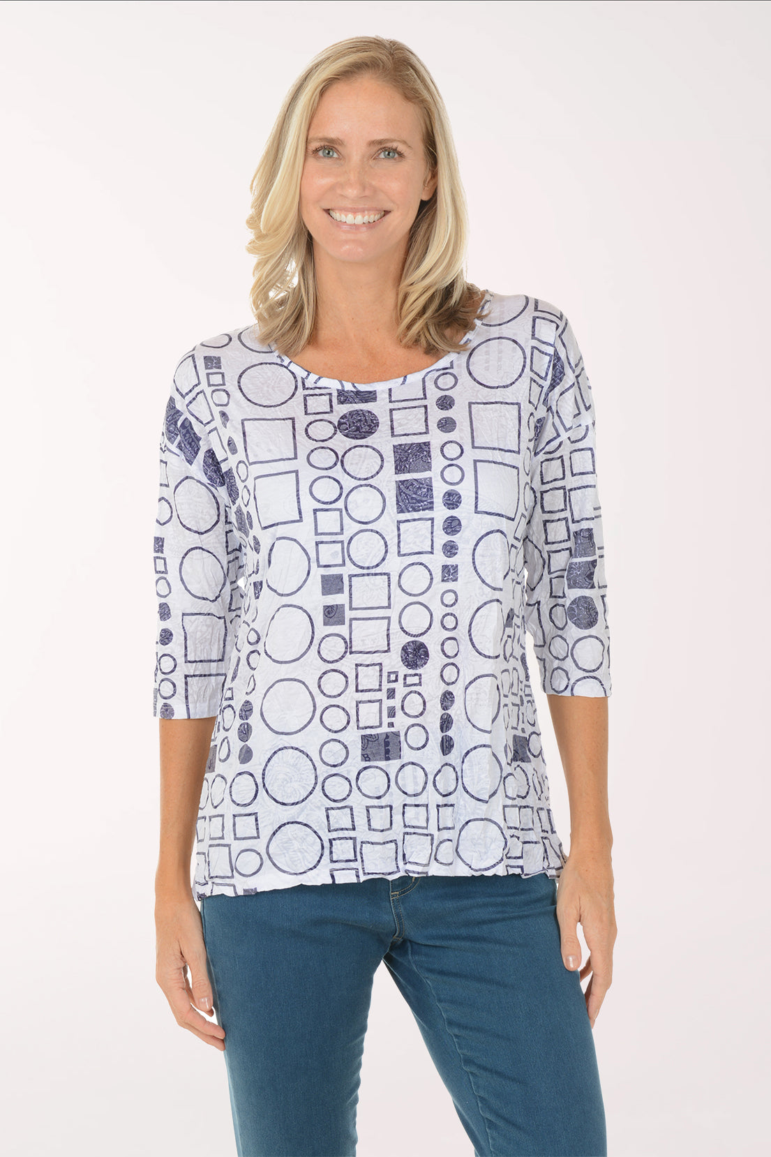 Woman wearing a patterned top with blue pants on a white background