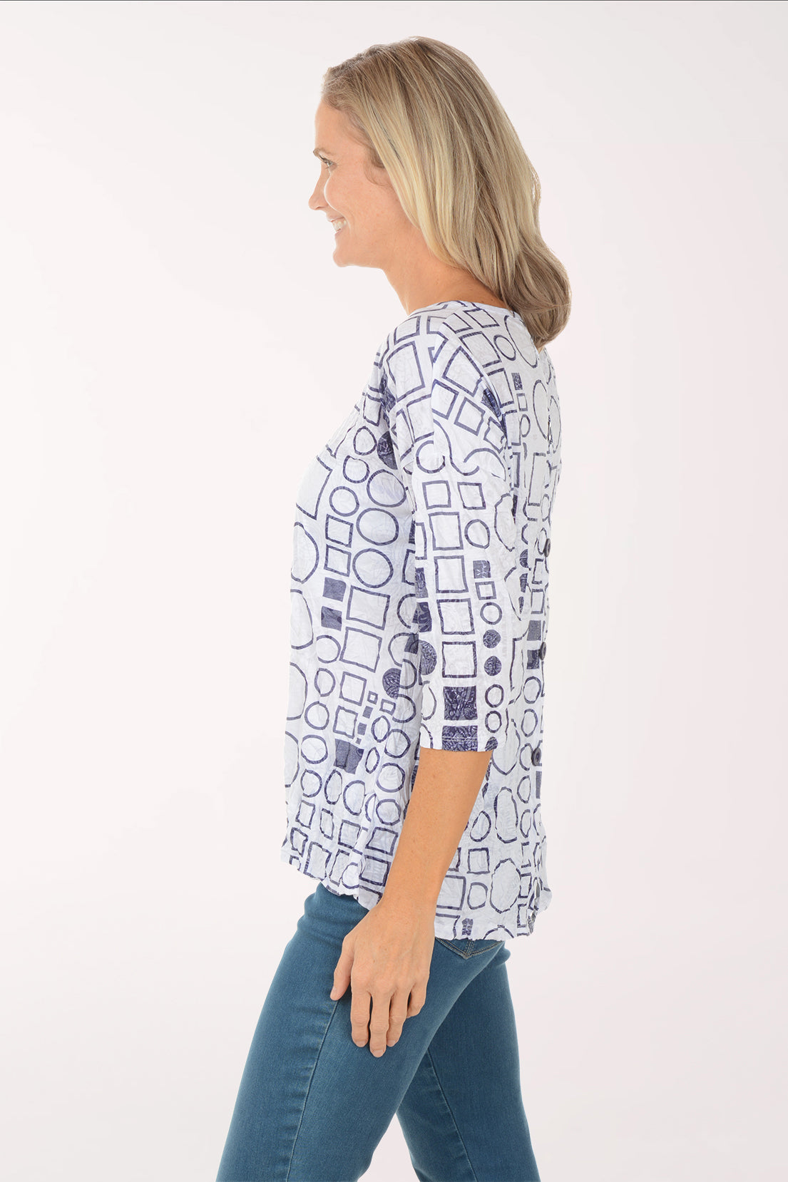 Woman wearing a patterned top with blue pants on a white background