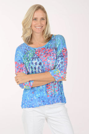Woman wearing a colorful floral-patterned top against a white background