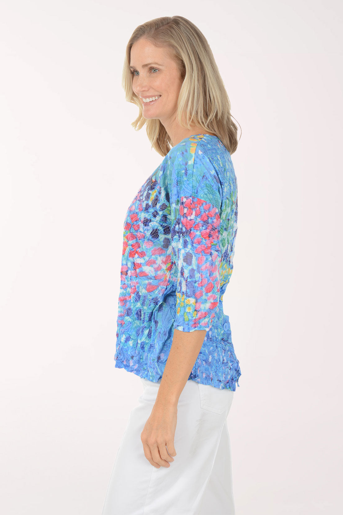 Woman wearing a colorful floral-patterned top against a white background