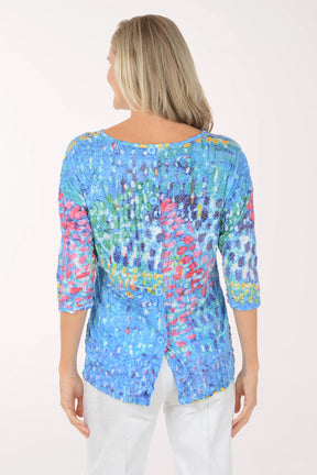 Woman wearing a colorful floral-patterned top against a white background