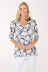 Woman wearing a patterned blouse and white pants on a white background