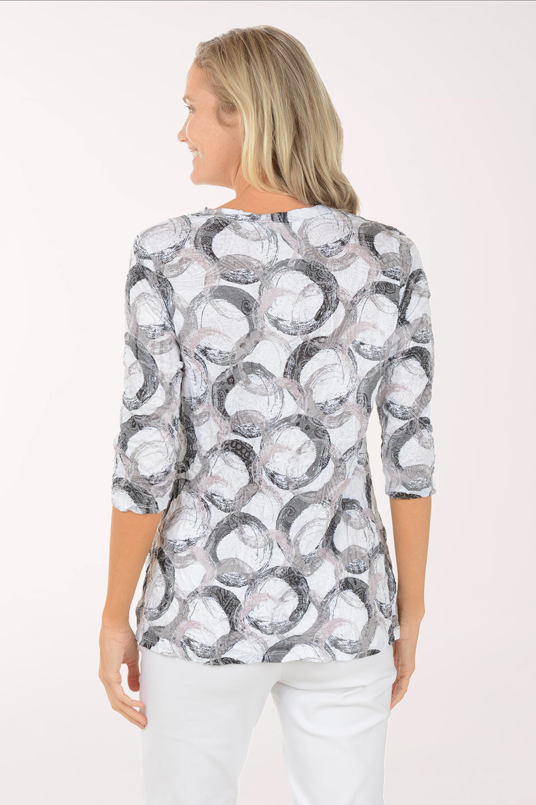 Woman wearing a patterned blouse and white pants on a white background