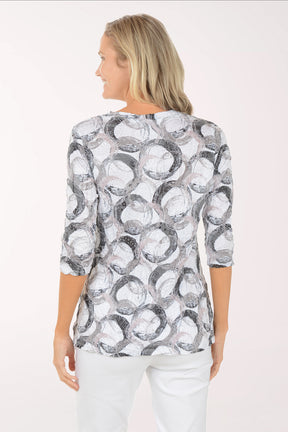 Woman wearing a patterned blouse and white pants on a white background