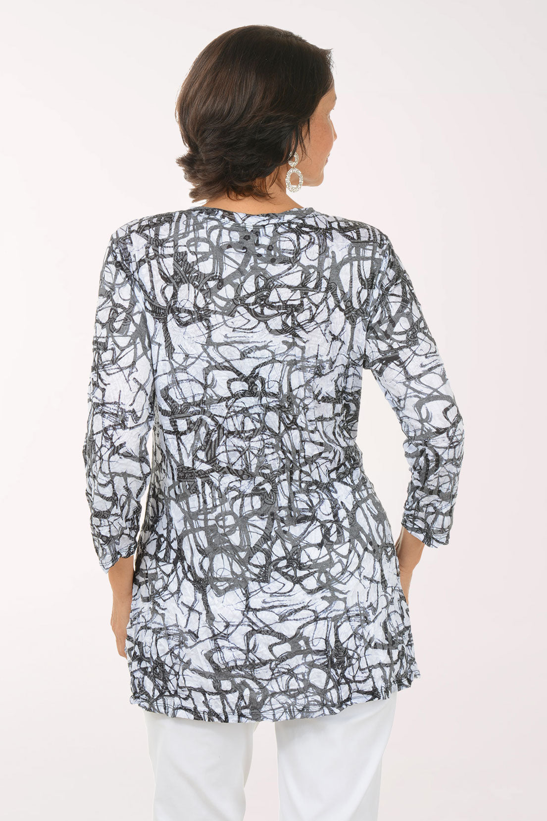 Woman wearing a black and white patterned top with 3/4 sleeves.