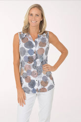 Woman wearing a sleeveless patterned top and white pants on a white background