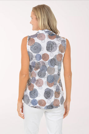 Woman wearing a sleeveless patterned top and white pants on a white background