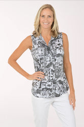 Woman wearing a sleeveless patterned top and white pants on a white background