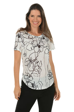 Woman wearing a black and white floral patterned top on a white background.