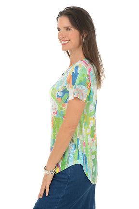 Woman wearing a colorful patterned shirt with a white background. Side shot.
