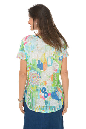 Woman wearing a colorful patterned shirt with a white background. Back shot.