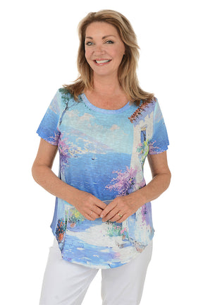 Woman wearing a colorful beach-themed t-shirt with a scenic design.