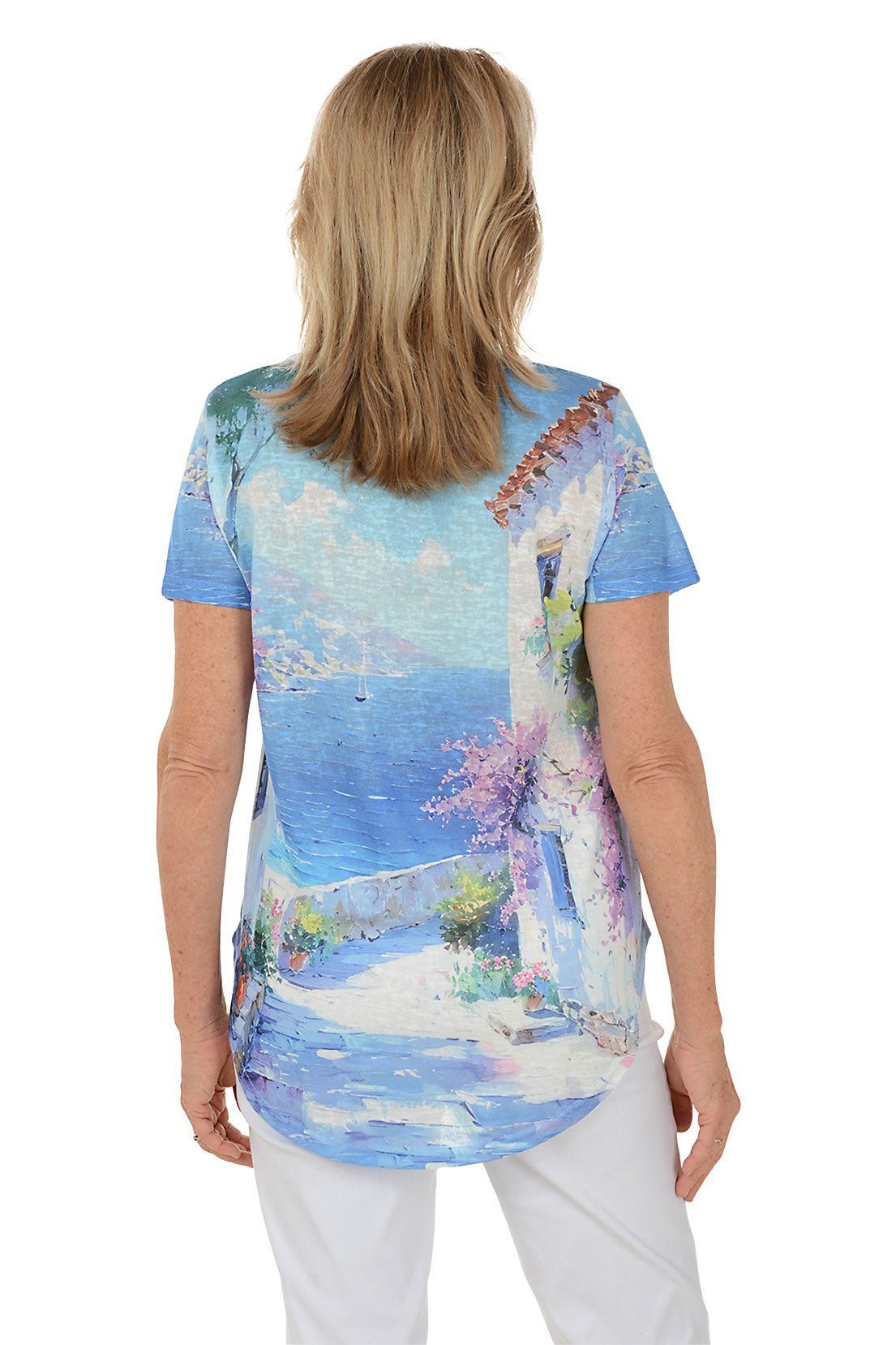 Woman wearing a colorful beach-themed t-shirt with a scenic design. Back shot.