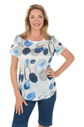 Woman wearing a blue and white patterned top with denim shorts on a white background