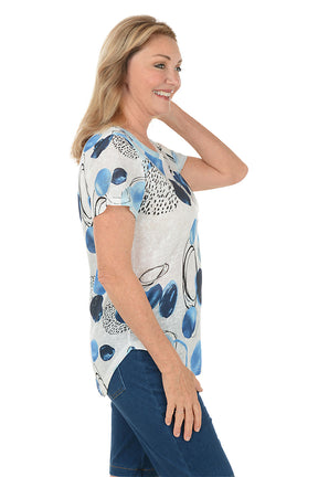 Woman wearing a blue and white patterned top with denim shorts on a white background