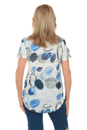 Woman wearing a blue and white patterned top with denim shorts on a white background