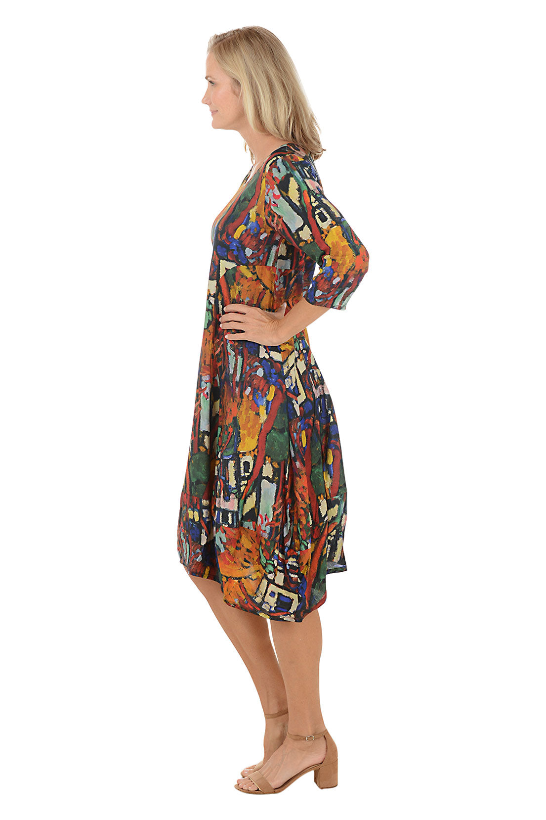 A woman wearing a 3/4 sleeve dress with a multi-colored patterned. Side shot.